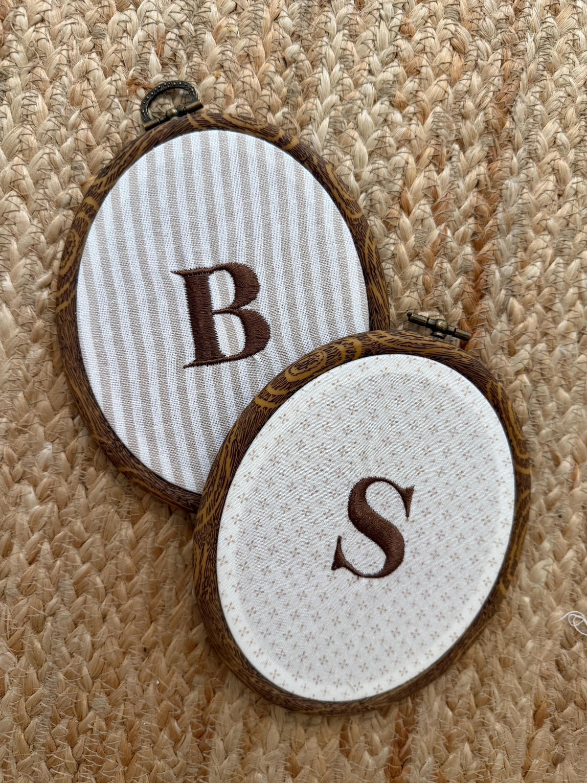 Two embroidery hoops: striped hoop with B and white hoop with S on star-dotted fabric, ties.