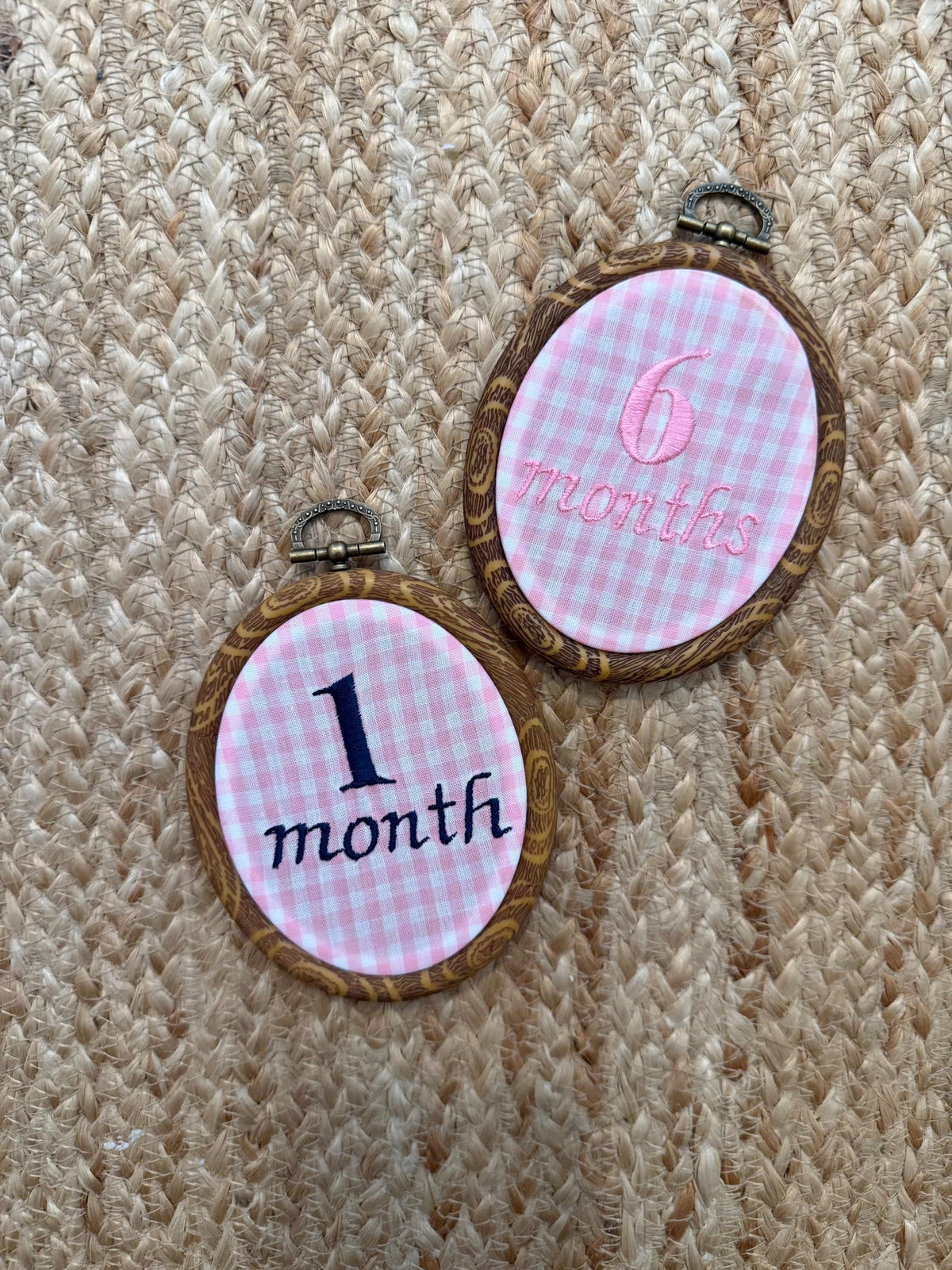 Hanging oval milestone discs reading '1 month' and '6 months' on gingham
