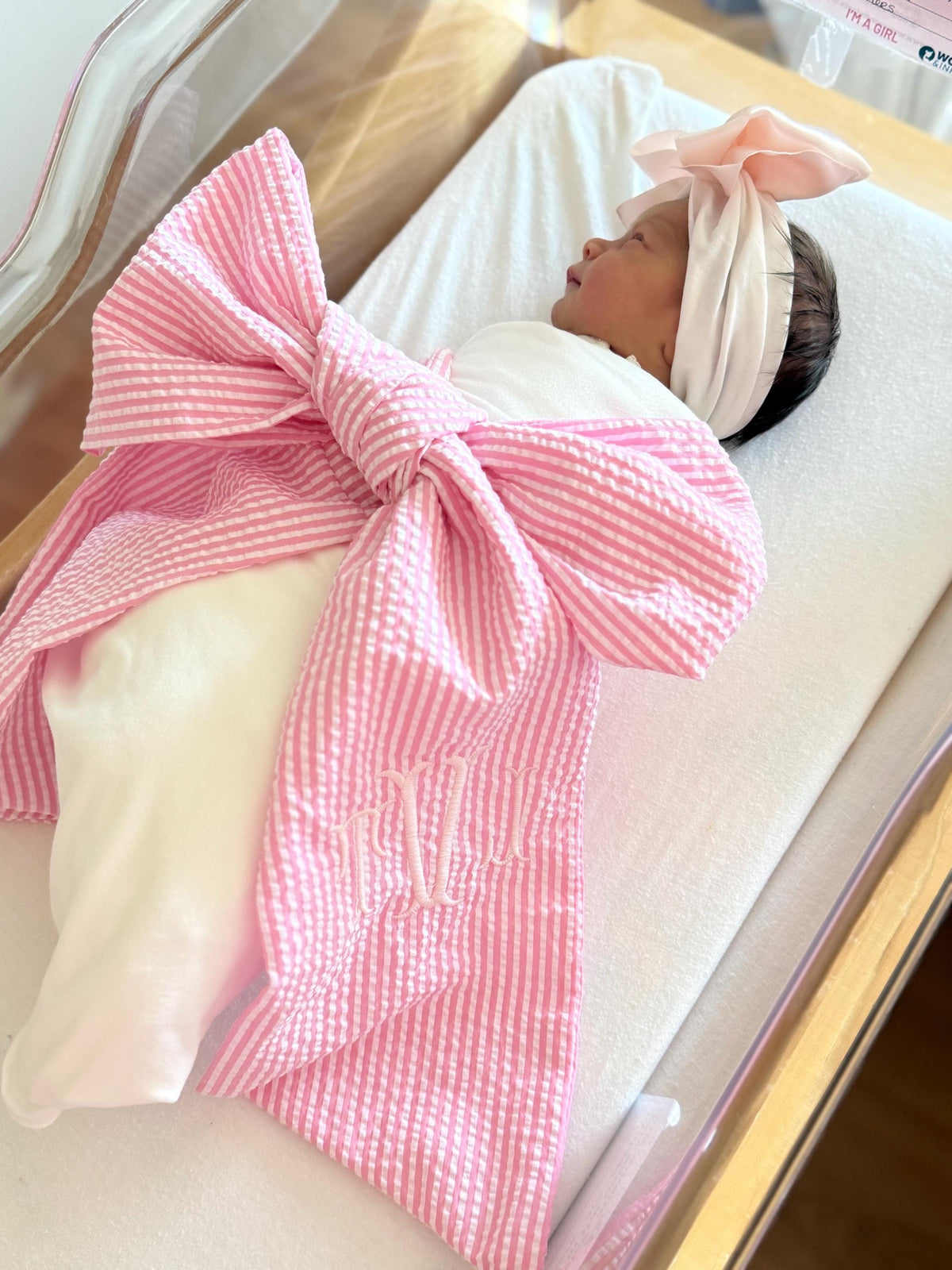 Pink seersucker newborn bow sash with large tied bow and gold monogram