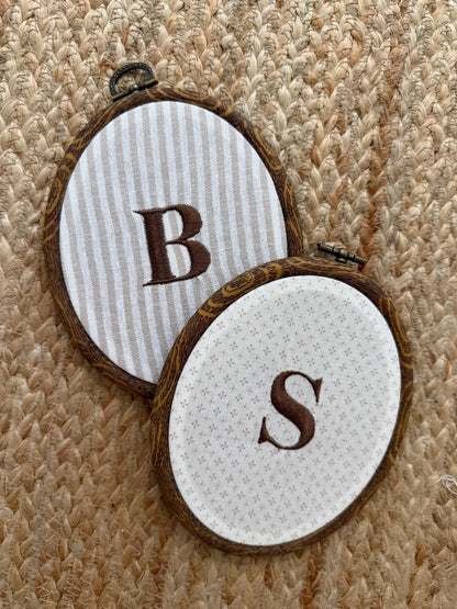 Two embroidery hoops: striped hoop with B and white hoop with S on star-dotted fabric, ties.