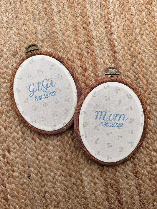 Two embroidered hoop signs: Mom Est.2022 and Gigi Est.2022 with floral accents
