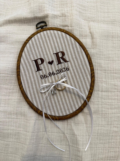 Wood-look embroidery hoop with striped fabric, initials P.R and date 06.06.2026, ribbon bow.