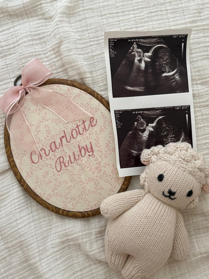 Pink floral oval baby name reveal sign with pink ribbon and small knit bunny