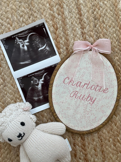 Pink floral oval baby name sign with embroidered names, plush lamb and ultrasound cards